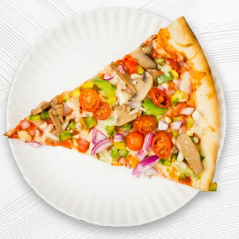 A colorful slice of vegetarian pizza with mushrooms, bell peppers, onions, and cherry tomatoes on a white paper plate.