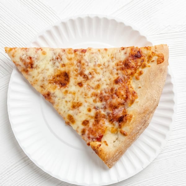 A single slice of cheese pizza with a golden-brown crust on a white paper plate.