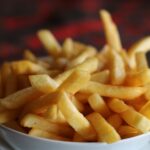 Delicious crispy kosher golden french fries served in a white bowl, perfect for a tasty snack.