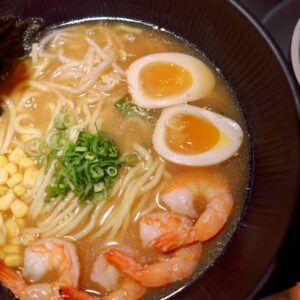Mouthwatering shrimp ramen with soft-boiled egg, corn, and scallions in savory broth.
