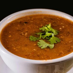 Warm bowl of lentil soup garnished with fresh cilantro leaves, perfect for cozy dining.